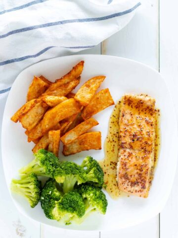 a well rounded meal of salmon, wedge fries, and steamed broccoli