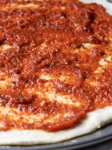 pizza marinara sauce spread on pizza crust