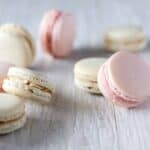 scattered strawberry and french vanilla french macarons on a white background
