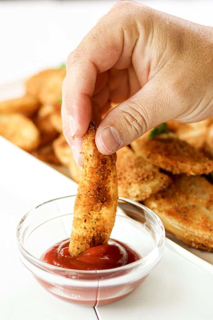 a crispy baked wedge fry getting dipped in ketchup