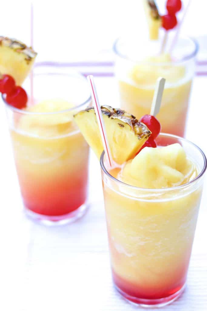 the perfect summer blended drink poured over grenadine and garnished with maraschino cherries and fresh pineapple slices