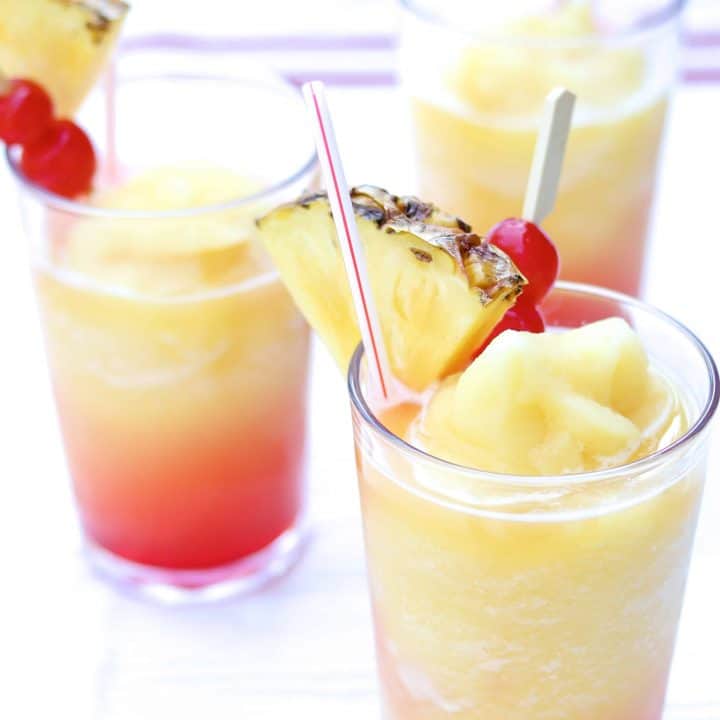 the perfect summer blended drink poured over grenadine and garnished with maraschino cherries and fresh pineapple slices