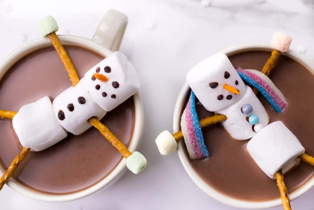 two marshmallow snowmen floating in the hot chocolate