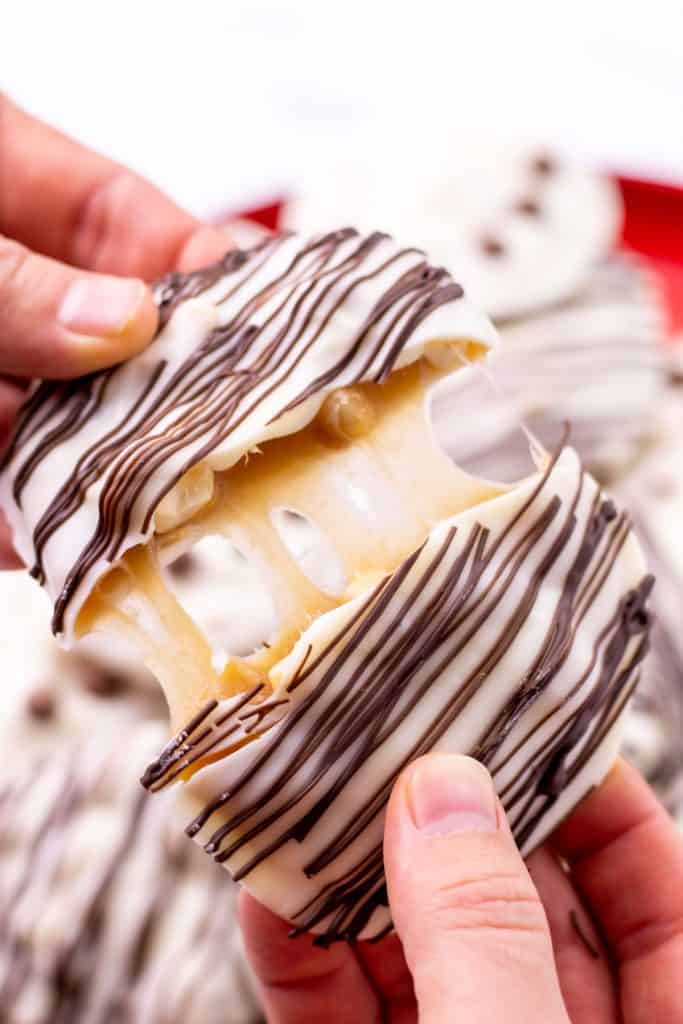 pulling a polar bear claw cookie apart to reveal the caramel peanut inside