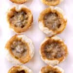A bunch of butter tarts on a white serving tray.