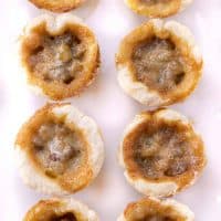 A bunch of butter tarts on a white serving tray.