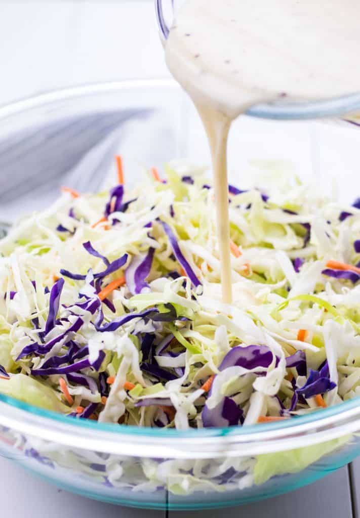 pouring the coleslaw dressing onto the salad