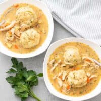 chicken and dumpling stew served in white bowls with two dumplings per bowl