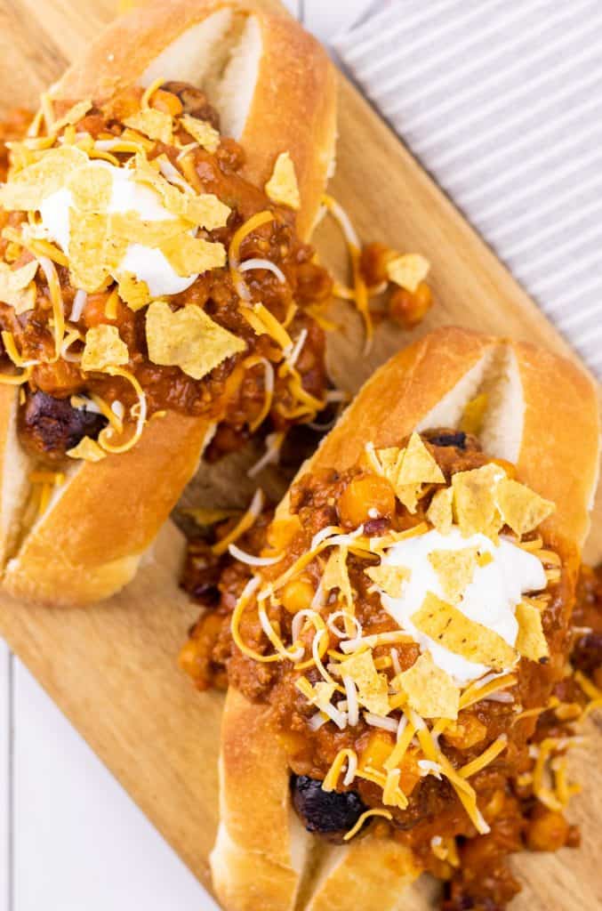 Fully loaded chili dogs, prepared and served on a wooden serving board