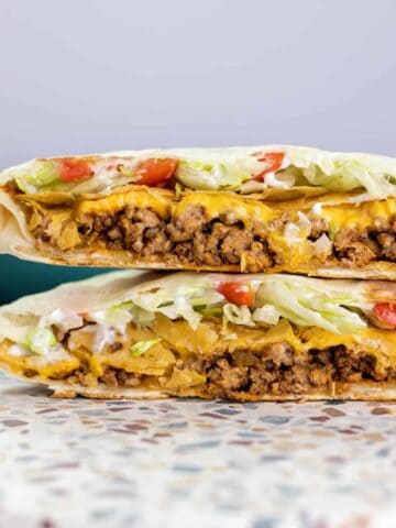 a cooked crunchwrap supreme cut in half and stacked to show the layers within