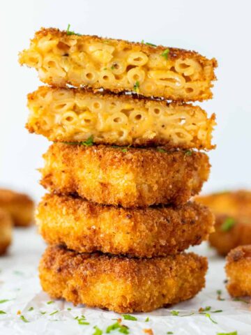 a stack of mac and cheese bites with the top two cut open to expose the cheesy insides