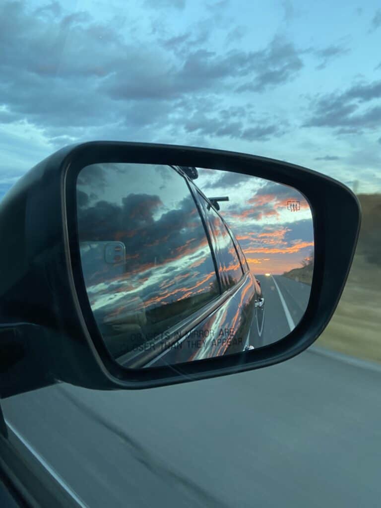 the sun rising in our rearview mirror while driving to the cabin