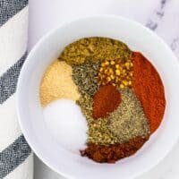 all of the ingredients to make taco seasoning in a small white mixing bowl