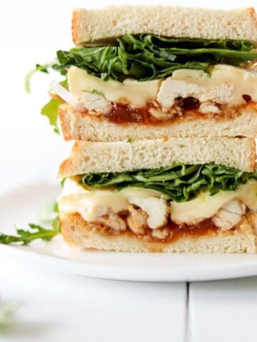 Apricot brie chicken sandwich stacked on a white plate