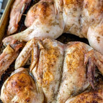 Two roasted chicken on a baking sheet.