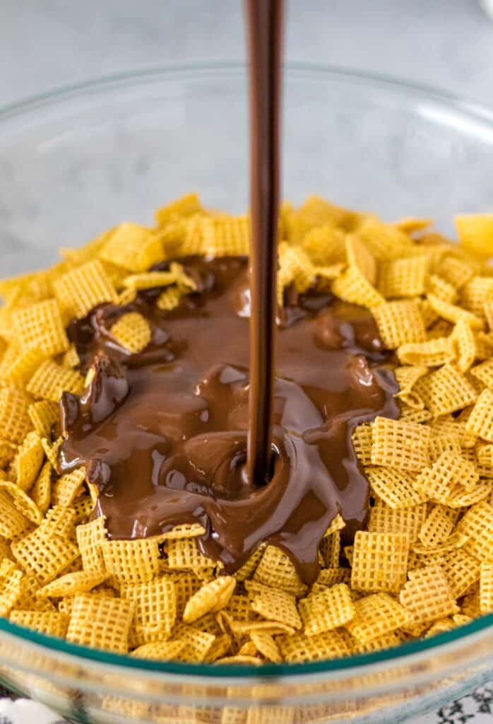pouring the melted chocolate and peanut butter over top of chex cereal