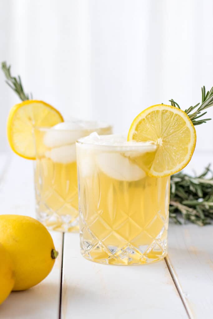 two lemon drop cocktails garnished with a lemon wheel and a sprig of fresh rosemary