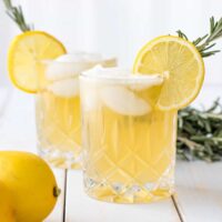 two lemon drop cocktails garnished with a lemon wheel and a sprig of fresh rosemary