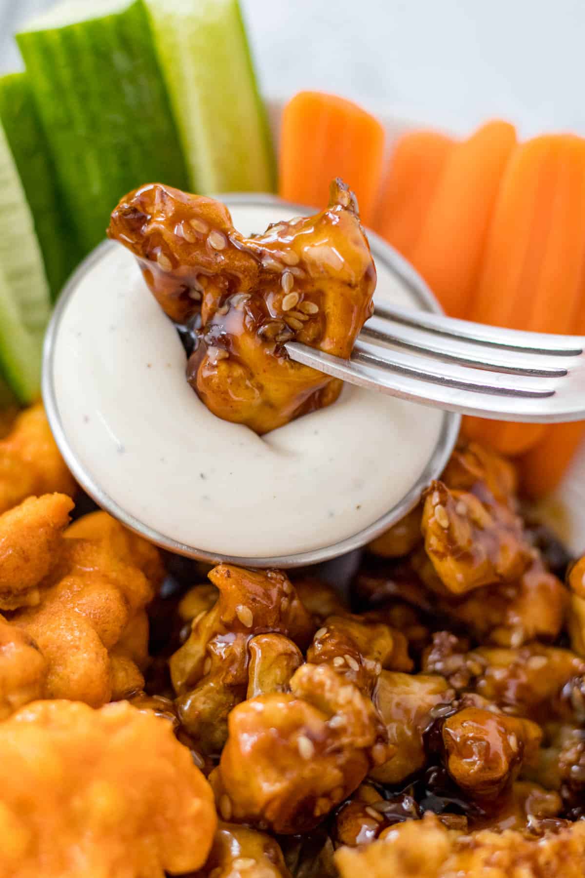 dipping a teriyaki cauliflower wing in the ranch dipping sauce