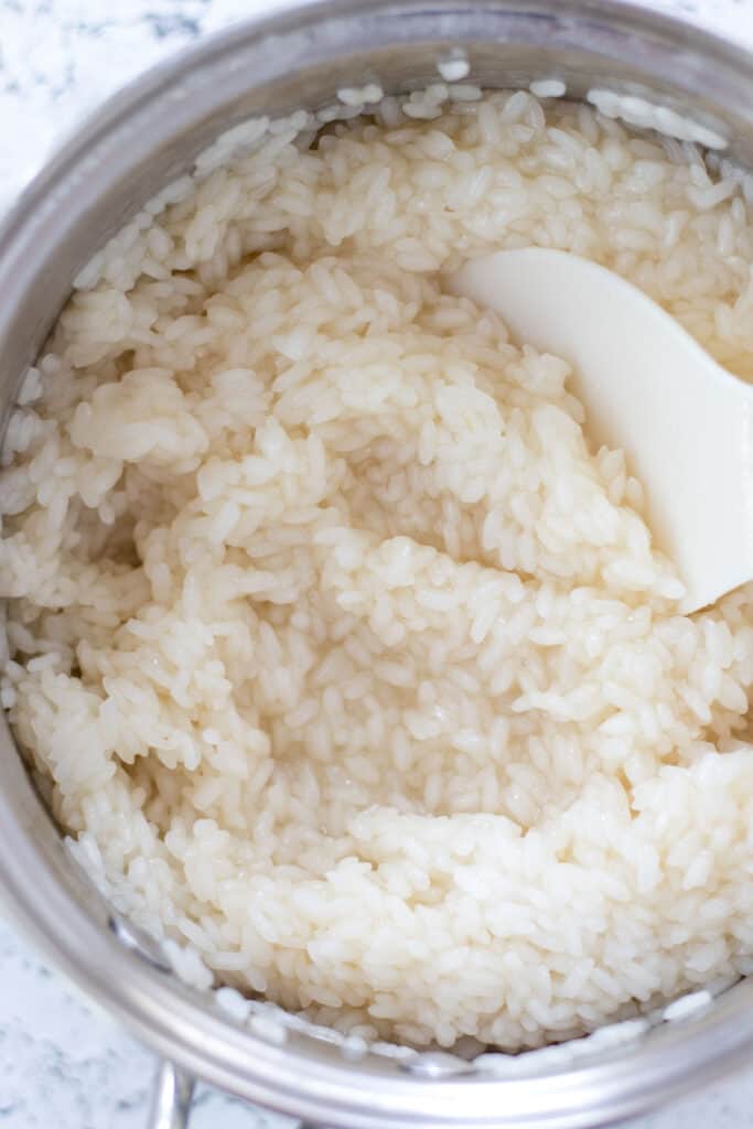 Sushi rice in a saucepan, stirring in the sushi rice seasoning.