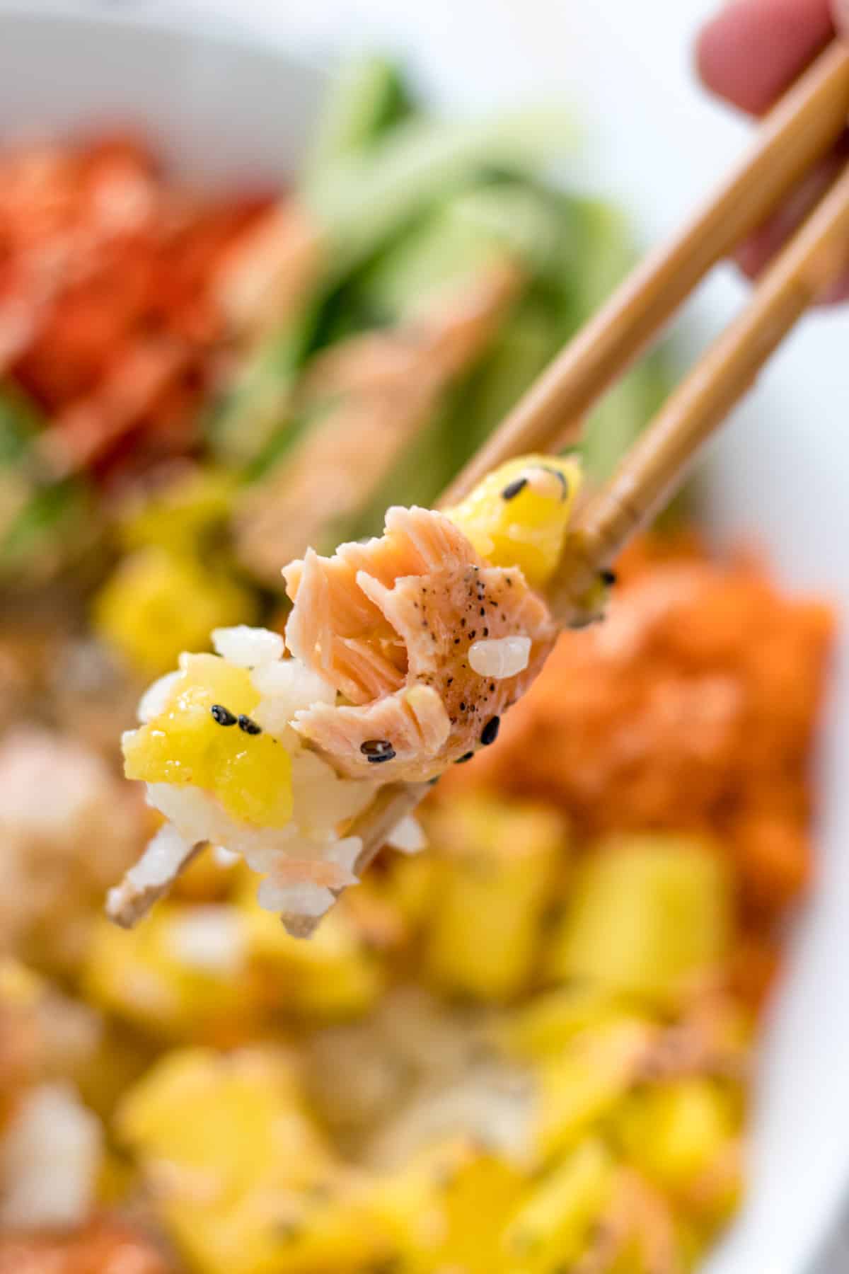 a bite of the sushi bowl on a pair of chopsticks