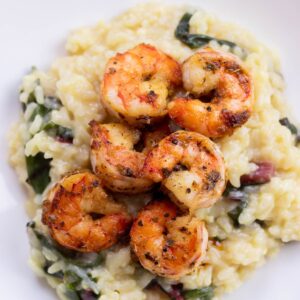 pan seared shrimp and swiss chard risotto on a white plate