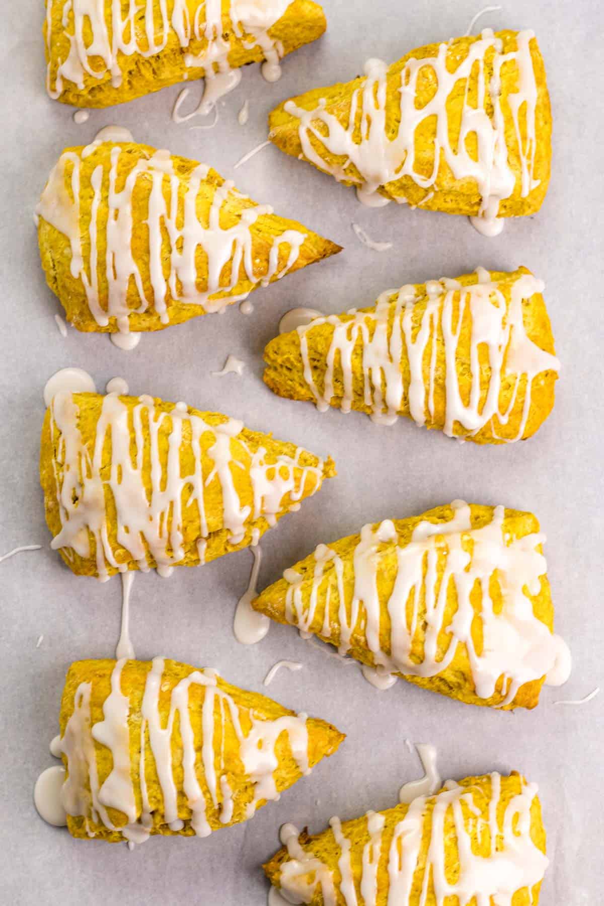 8 pumpkin scones after the frosting has been drizzled on top.