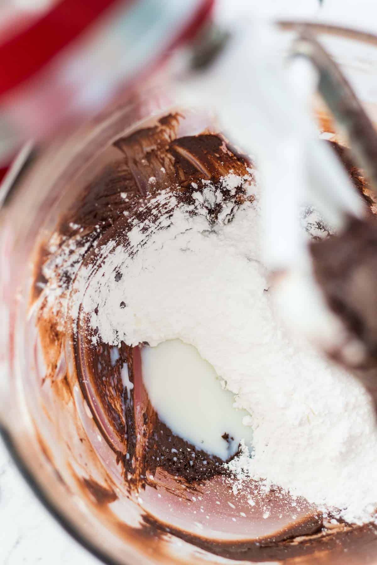 Adding the confectioners sugar and milk to the mixer.