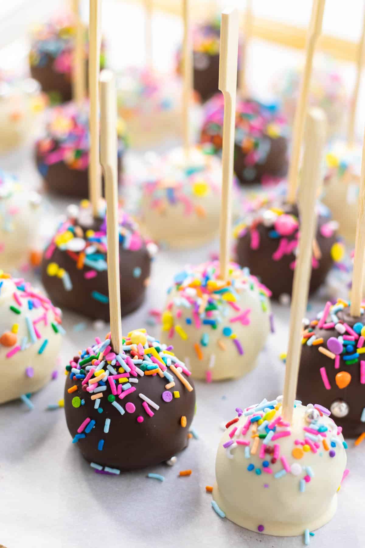 Homemade cake pops decorated with sprinkles on a baking sheet.