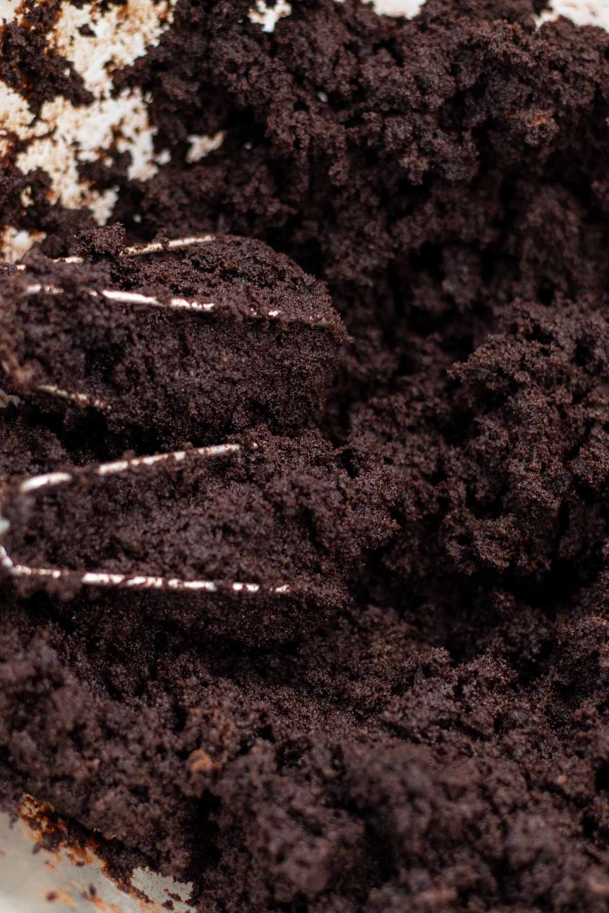 Mixing the chocolate buttercream into the crumbled cake with a hand mixer.