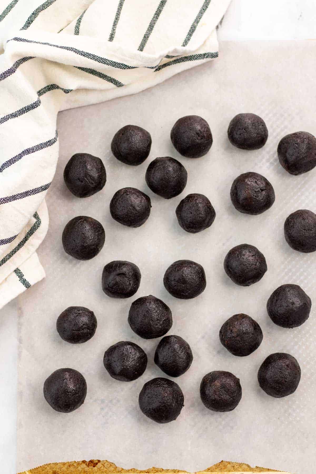 Cake balls rolled and placed on parchment paper on a baking sheet.