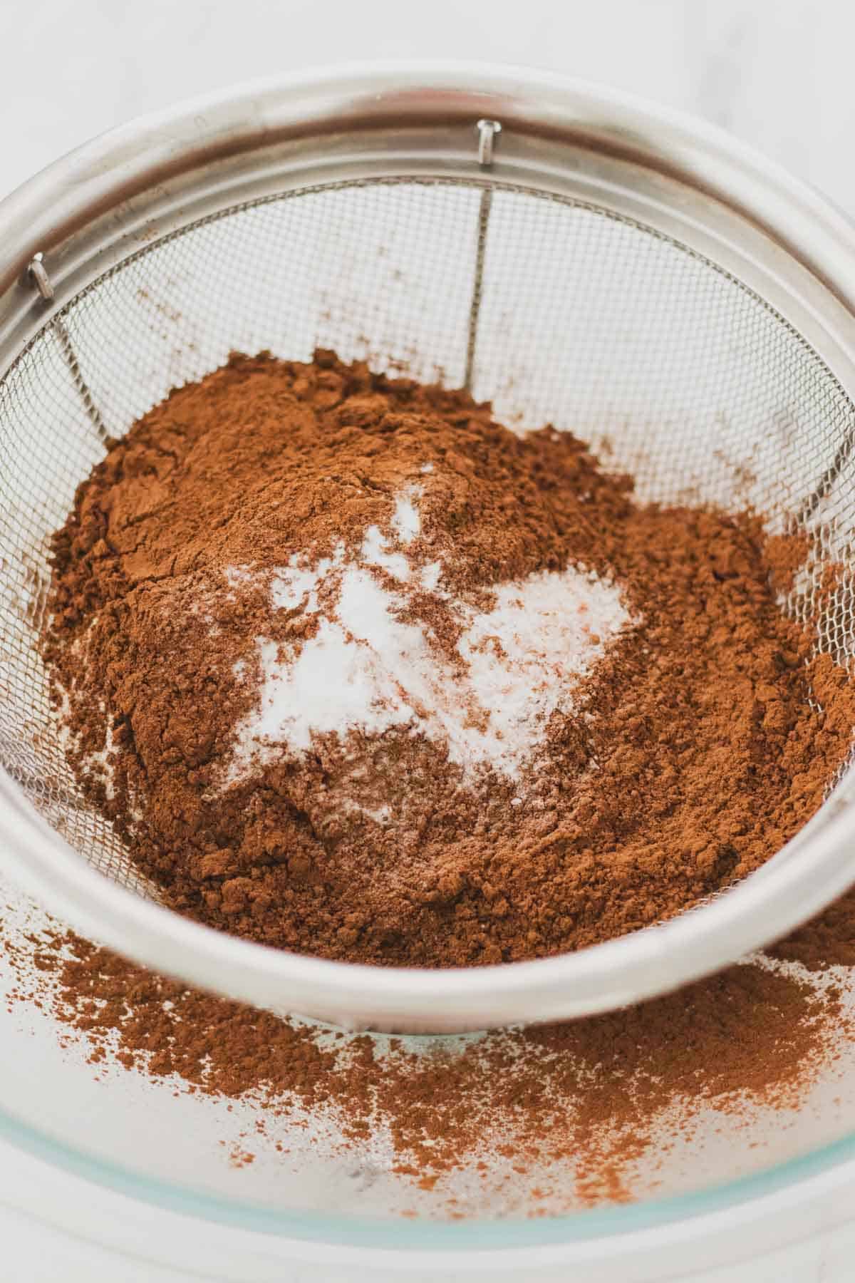 Dry ingredients in a fine mesh strainer in a large bowl.