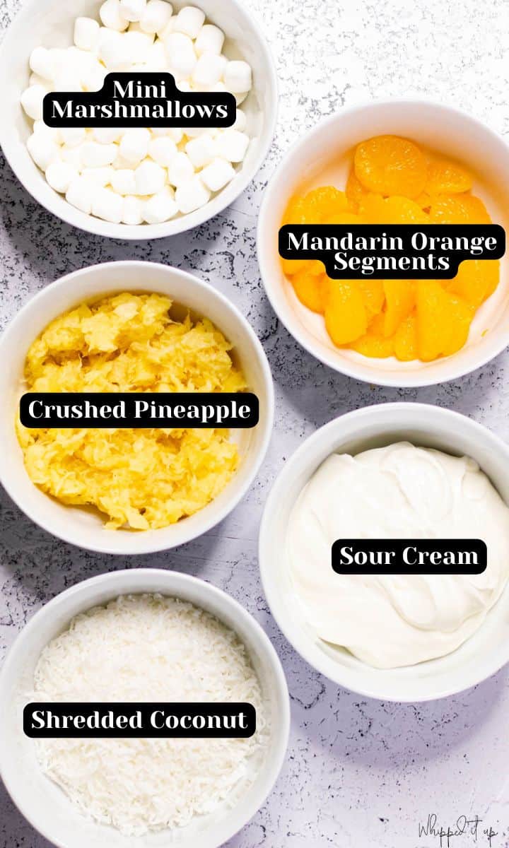 Ingredients to make ambrosia salad include: mini marshmallows, mandarin orange segments, crushed pineapple, sour cream, and shredded coconut.