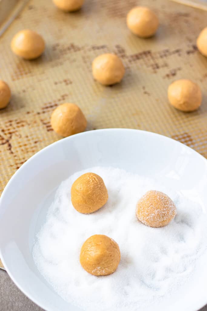 Rolling peanut butter cookie dough balls in sugar.