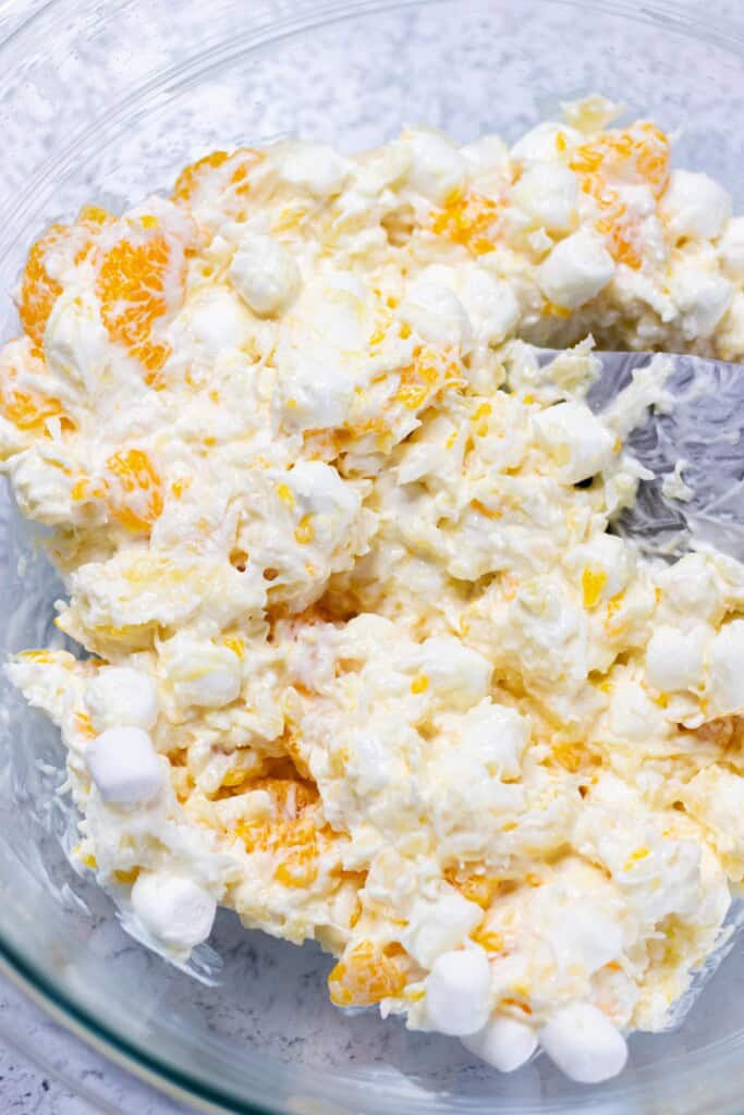 Gently mixing the ambrosia salad together with a spatula.