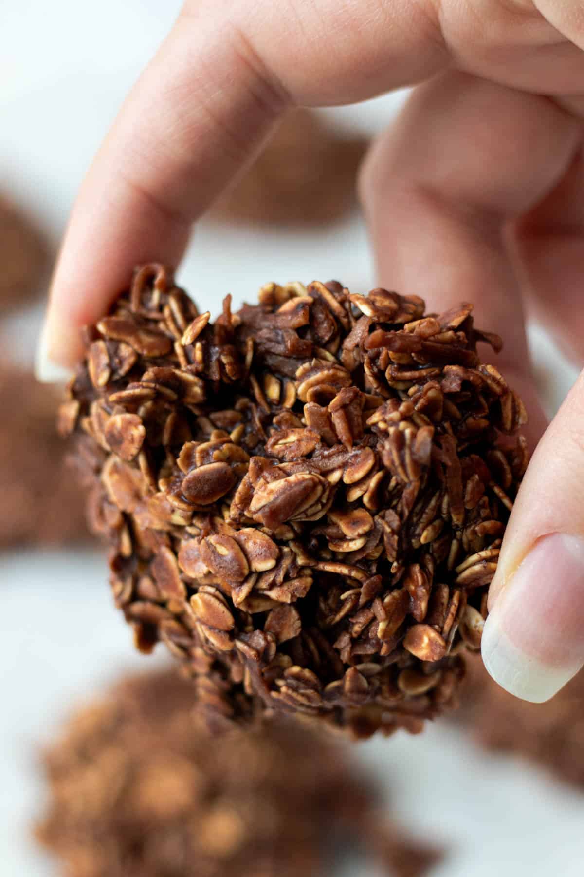 Holding a singular haystack cookie between two fingers.