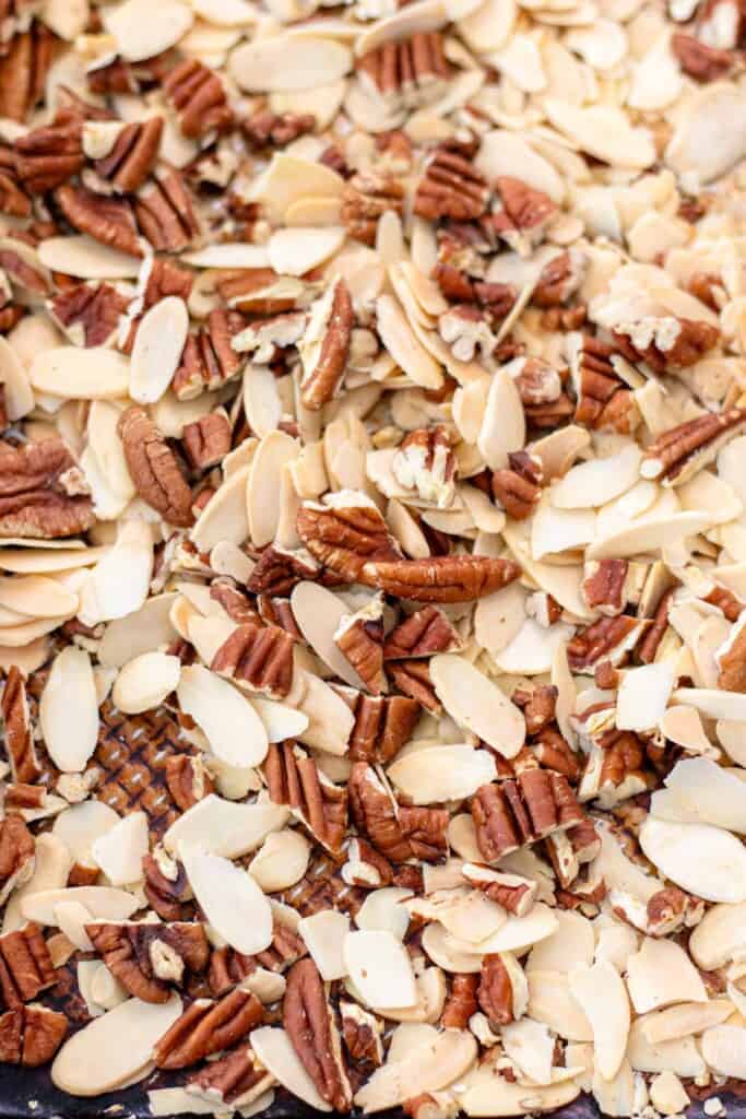Spreading the pecans and almonds on a baking sheet to toast in the oven.
