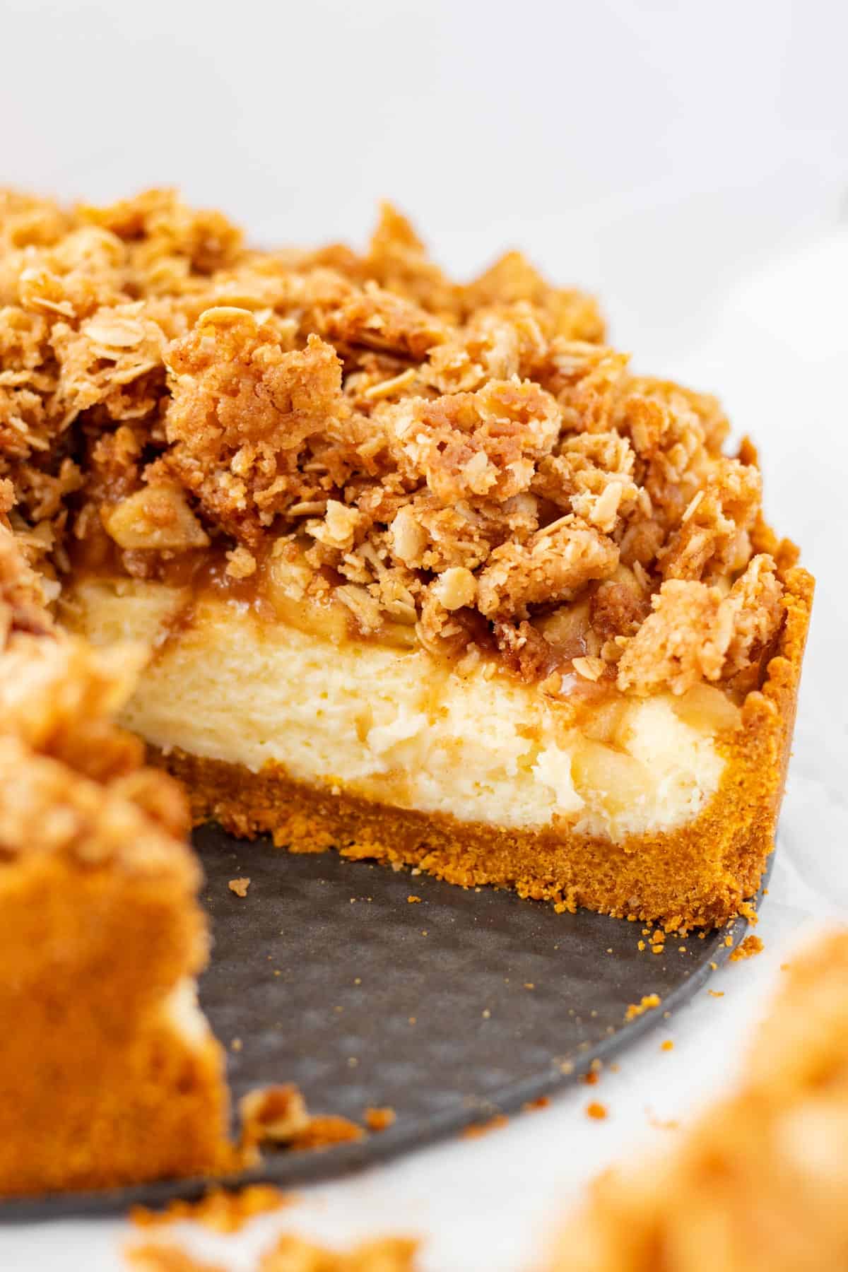 A cut section of cheesecake showing the apple and crumble layers.