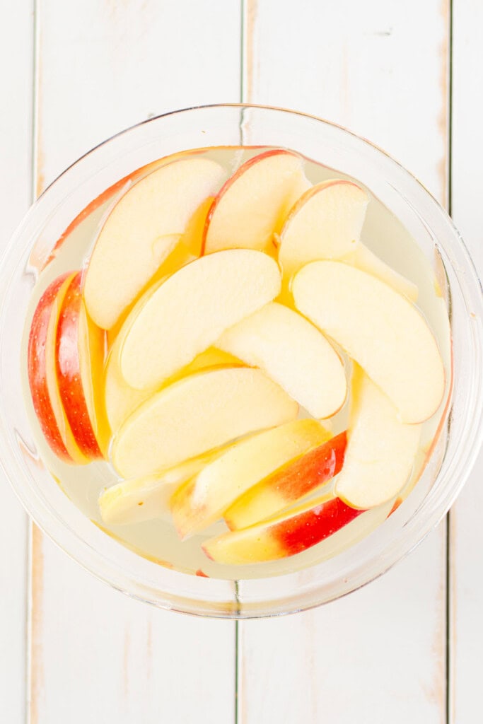 Apples soaking in a cold water lemon bath to prevent browning.