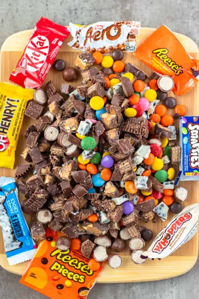 A cutting board filled with chopped halloween candy bars.