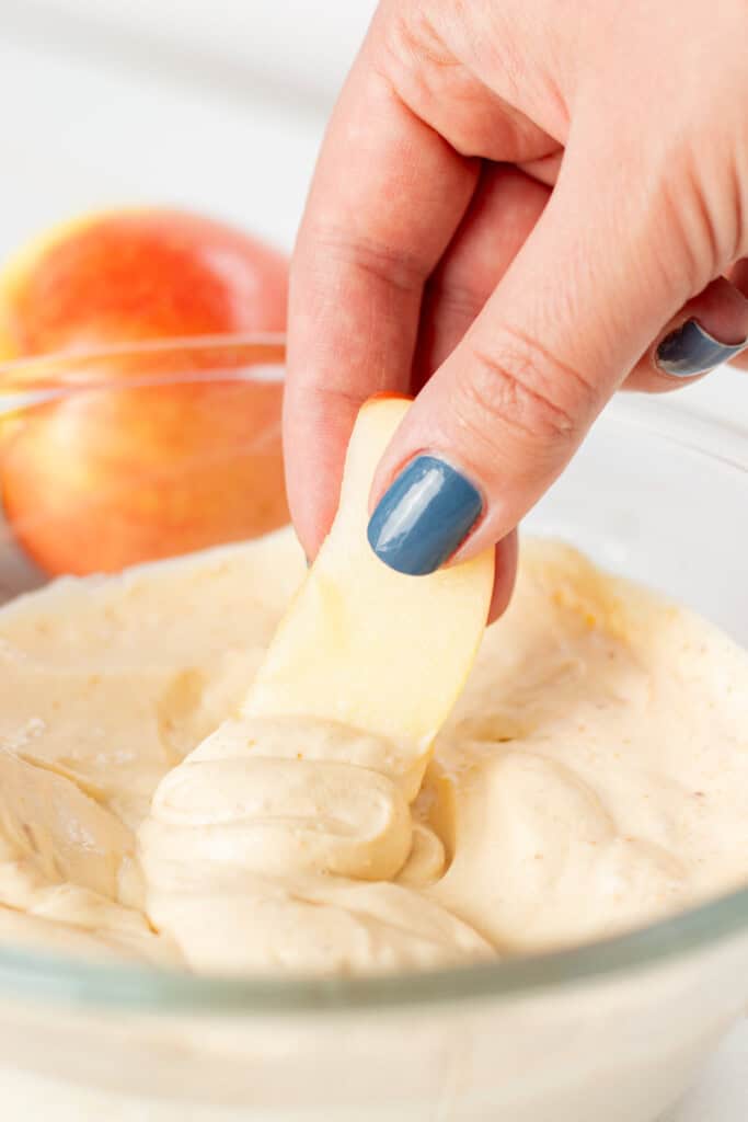 Dipping an apple slice into the prepared apple dip.
