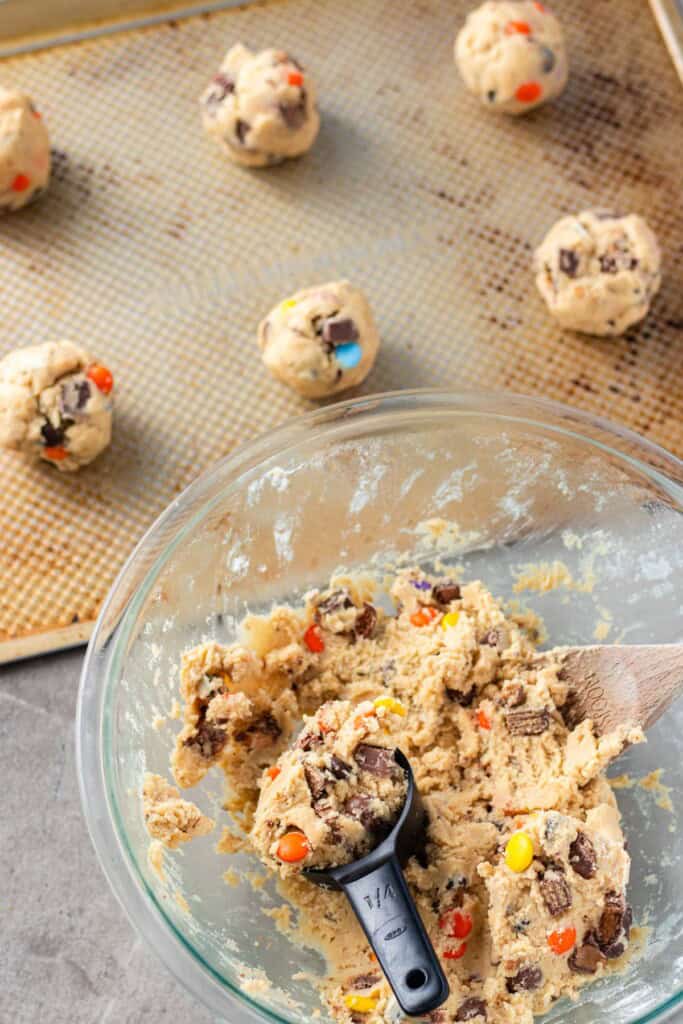 Portioning out the cookies, rolling them into a ball and placing them on a cookie sheet.