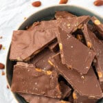 A blue bowl filled with milk chocolate almond bark.