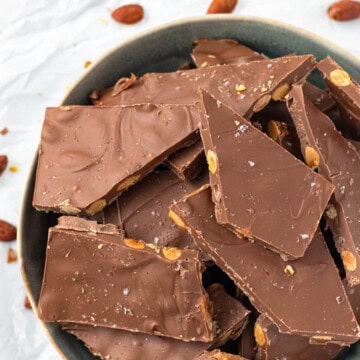 A blue bowl filled with milk chocolate almond bark.