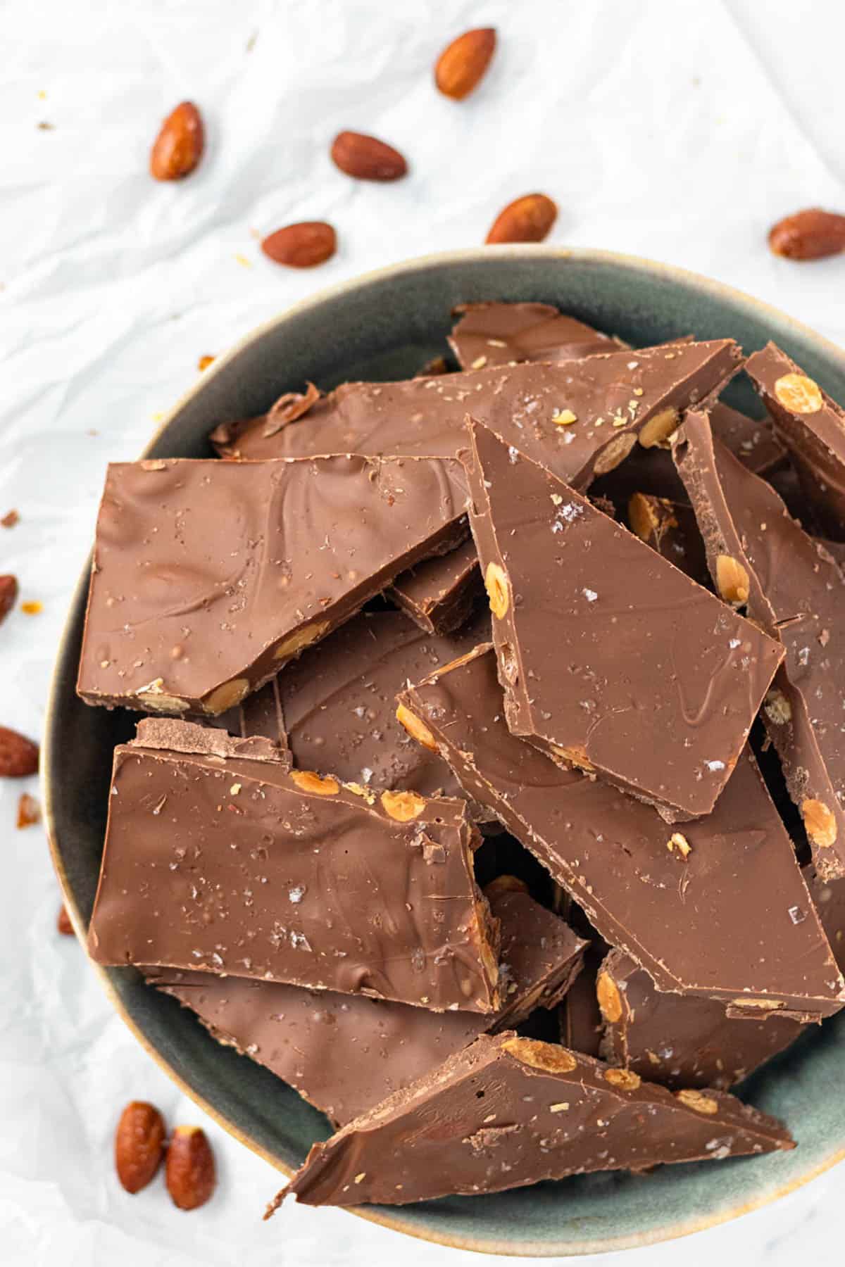 A blue bowl filled with milk chocolate almond bark.
