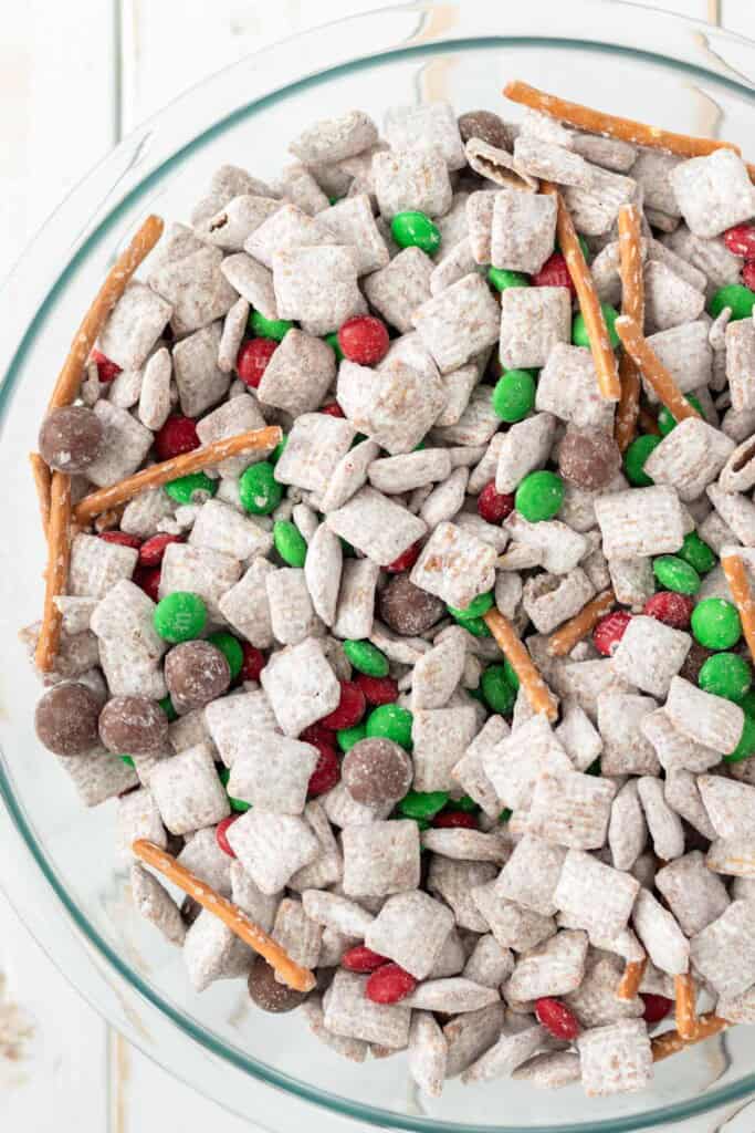 A large glass mixing bowl filled with christmas puppy chow.