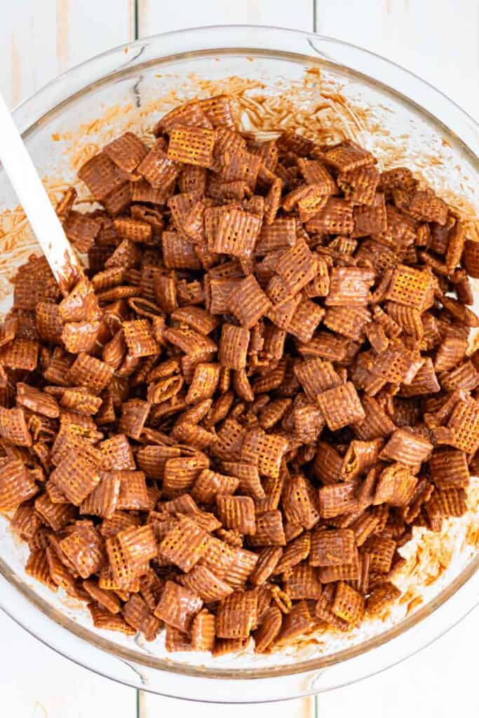 Stirring the Chex cereal with the melted chocolate peanut butter mixture.