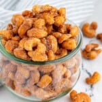 Honey roasted cashews piled high and spilling out of a glass jar.
