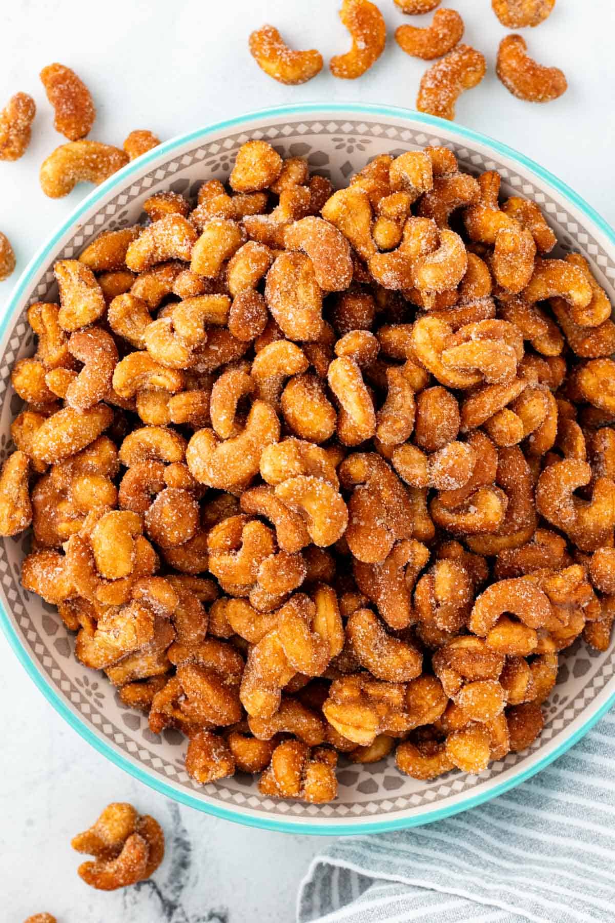 A large serving bowl filled with honey roasted cashews that have been tossed in cinnamon sugar.