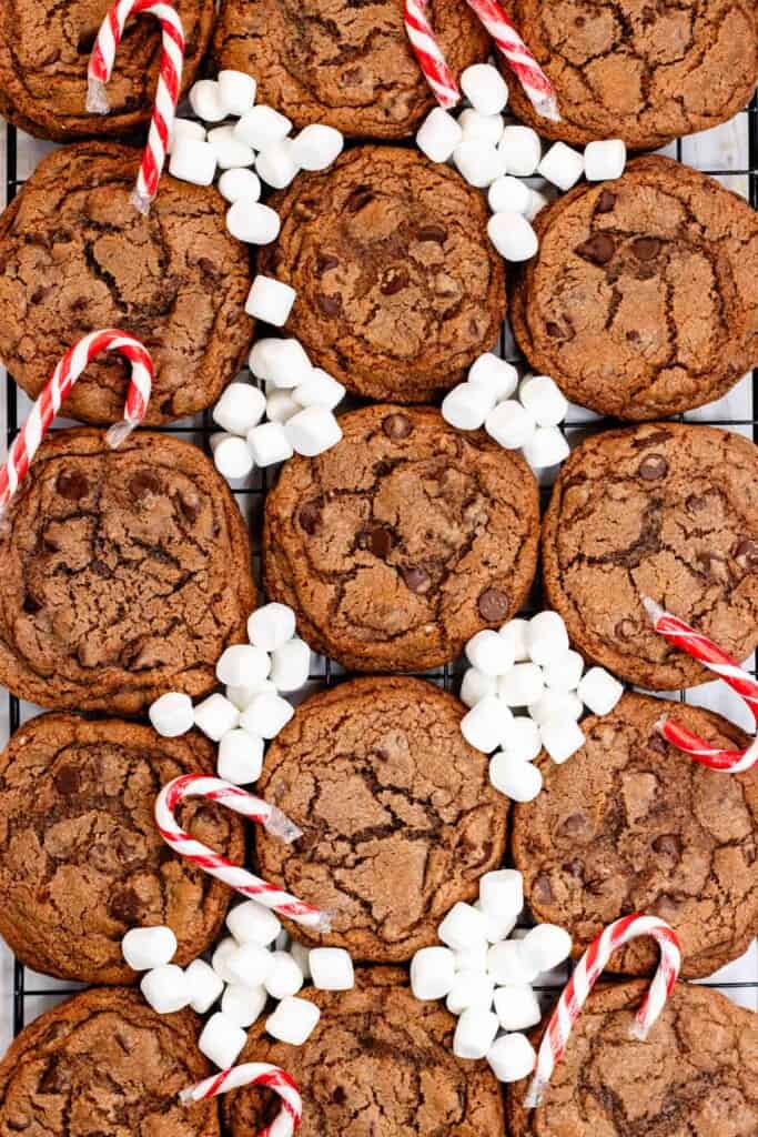 Hot chocolate cookies on a cooling rack with mini marshmallows and candy canes.
